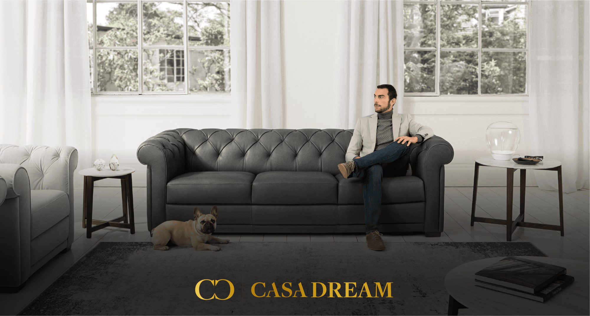 Lifestyle hero — gold logo overlaid on luxury living room scene with Chesterfield sofa and natural light